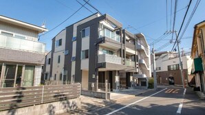A multi-story residential building with balconies, a gated entrance, and a clear sky. - Popular Shinjuku area Maximum12 People (Tokyo)