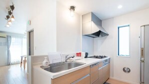 A modern kitchen with a stainless steel sink, a gas stove, and a built-in oven. There is a window providing natural light and a view of the outside. - Popular Shinjuku area Maximum12 People (Tokyo)