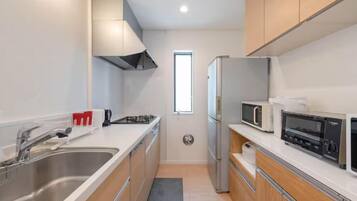 A modern kitchen with stainless steel appliances, wooden cabinets, and a large window providing natural light.