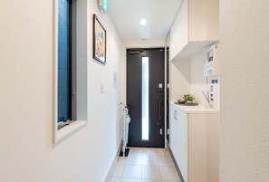 A narrow hallway with a door at the end, a radiator, and a small shelf with a plant.