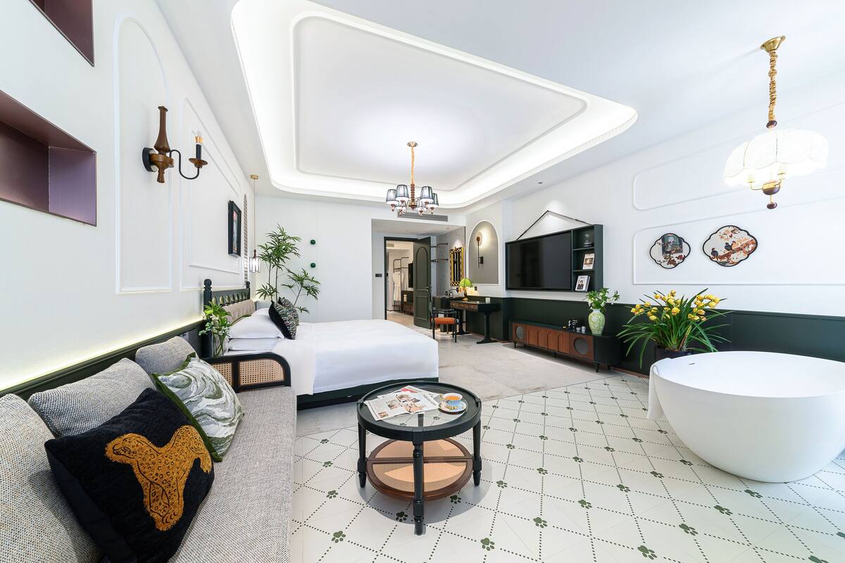 Una habitación de hotel moderna con una cama, una mesa redonda, una bañera blanca y un comedor.