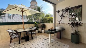 A patio with a table and chairs, a potted plant, and a view of a building with a dome. - Vishan Garden Boutique Hotel (Xiamen)
