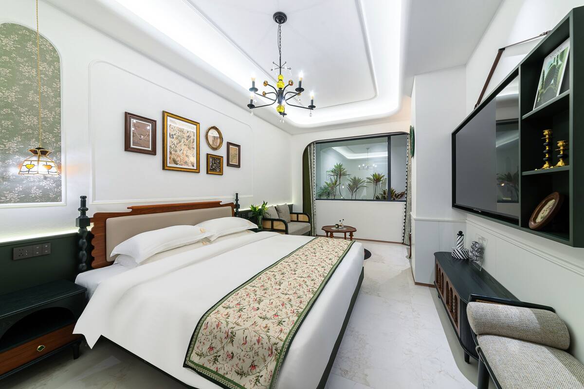 Un dormitorio con cama, televisión, escritorio y ventana.