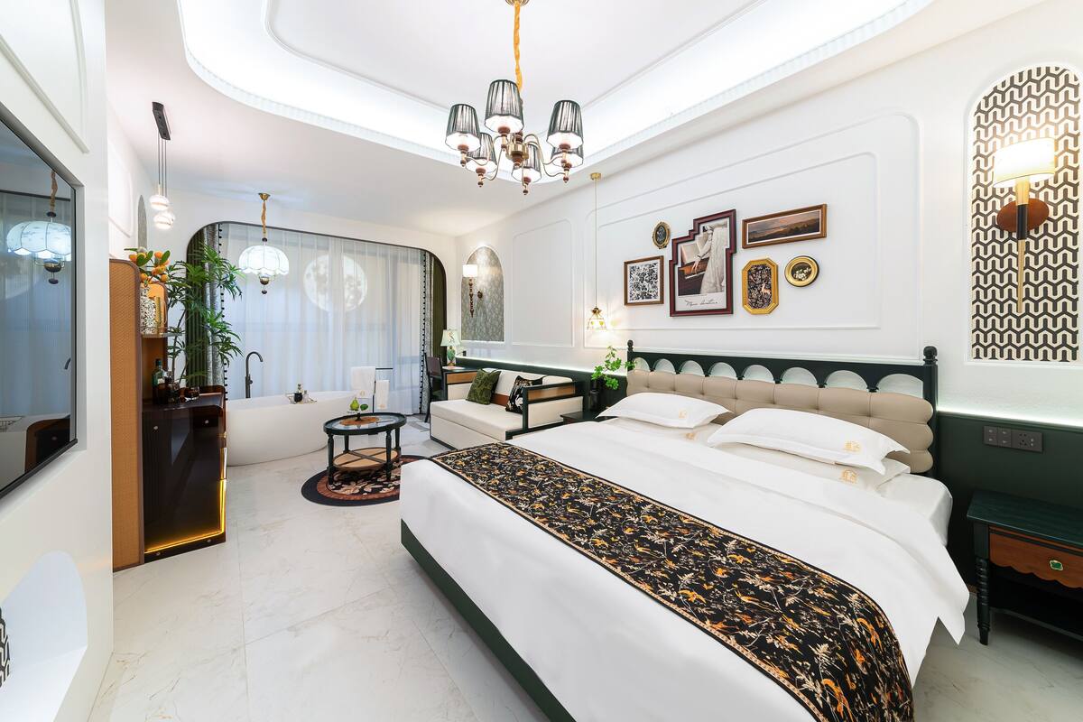 Una habitación de hotel moderna con una cama grande, un área de descanso, una bañera y una mesa de comedor.