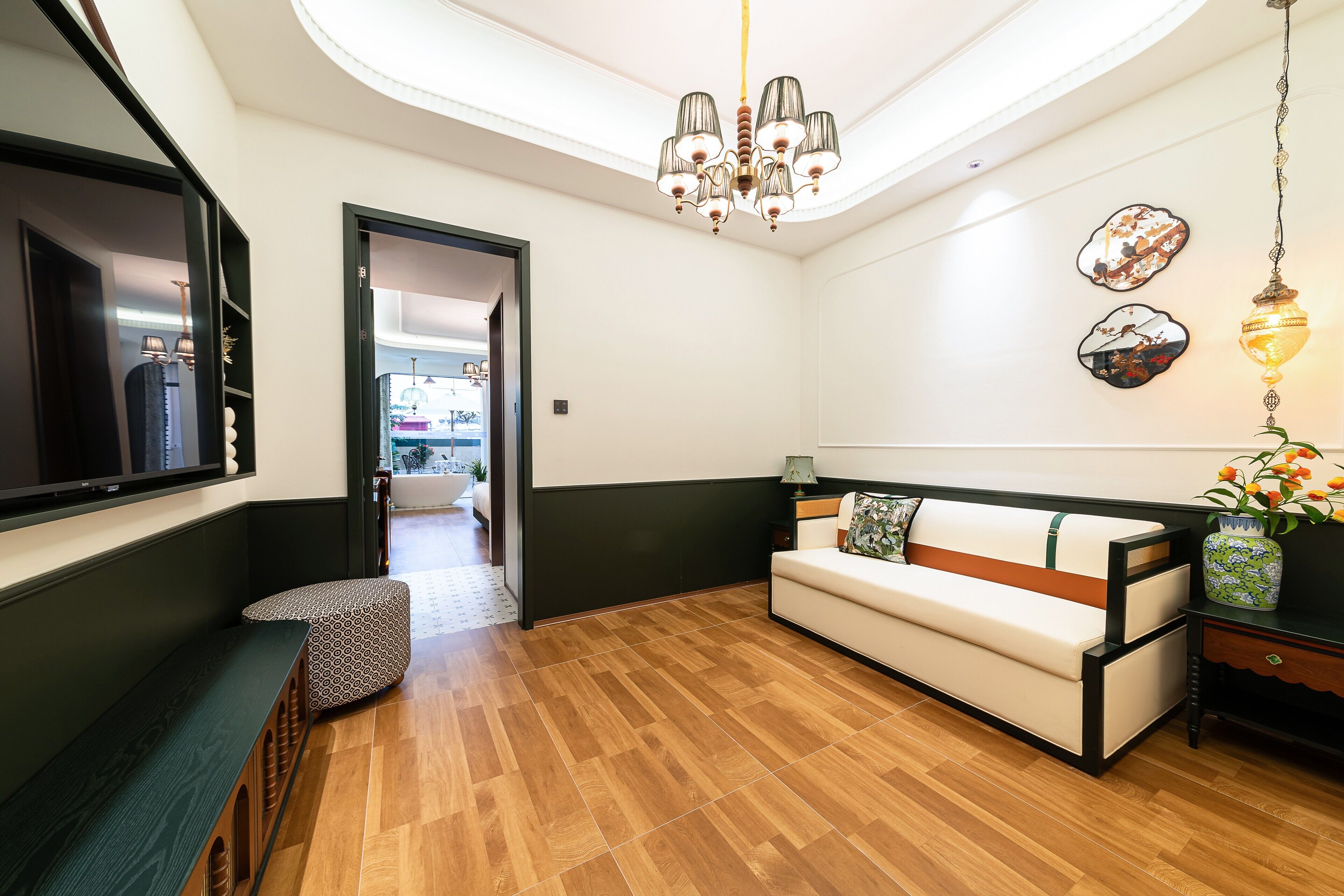 A modern living room with a wooden floor, a sofa, a bench, and a chandelier.