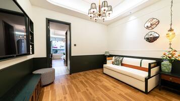 A modern living room with a wooden floor, a sofa, a bench, and a chandelier.