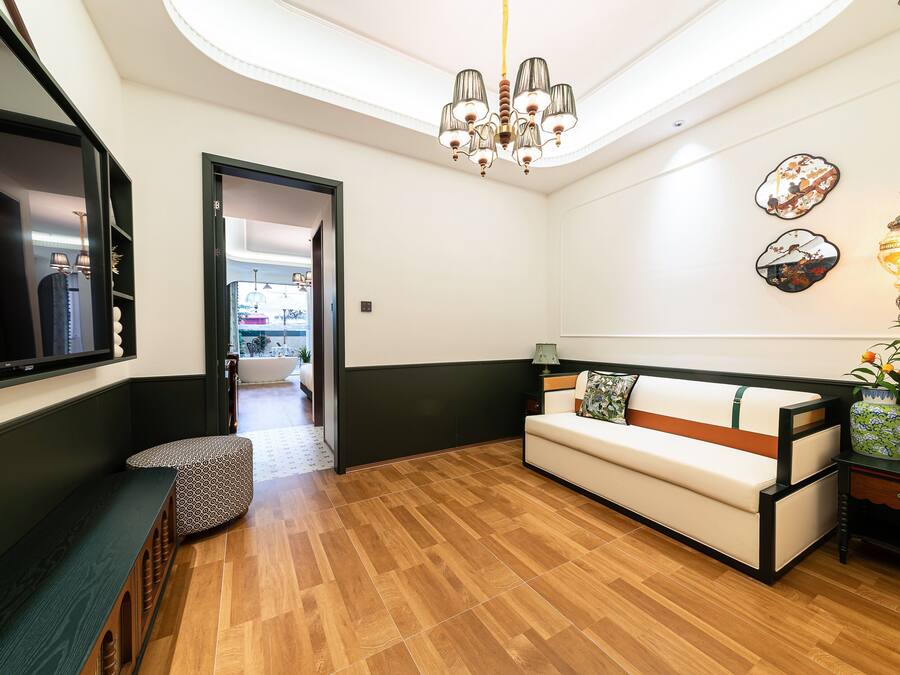 A modern living room with a wooden floor, a sofa, a bench, and a chandelier.