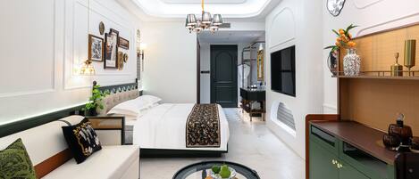 Une chambre d’hôtel moderne avec un lit, une table ronde ornée d’un vase, un canapé et un meuble vert.