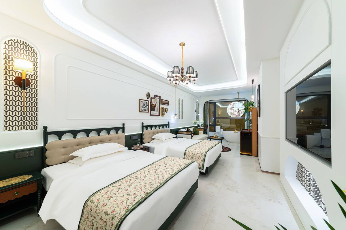 Una habitación de hotel moderna con dos camas, una araña y un espejo grande.
