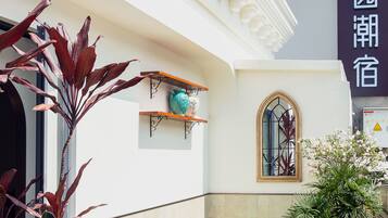 L’entrée d’un hôtel avec une piscine, des plantes en pot et une enseigne dans une langue étrangère.