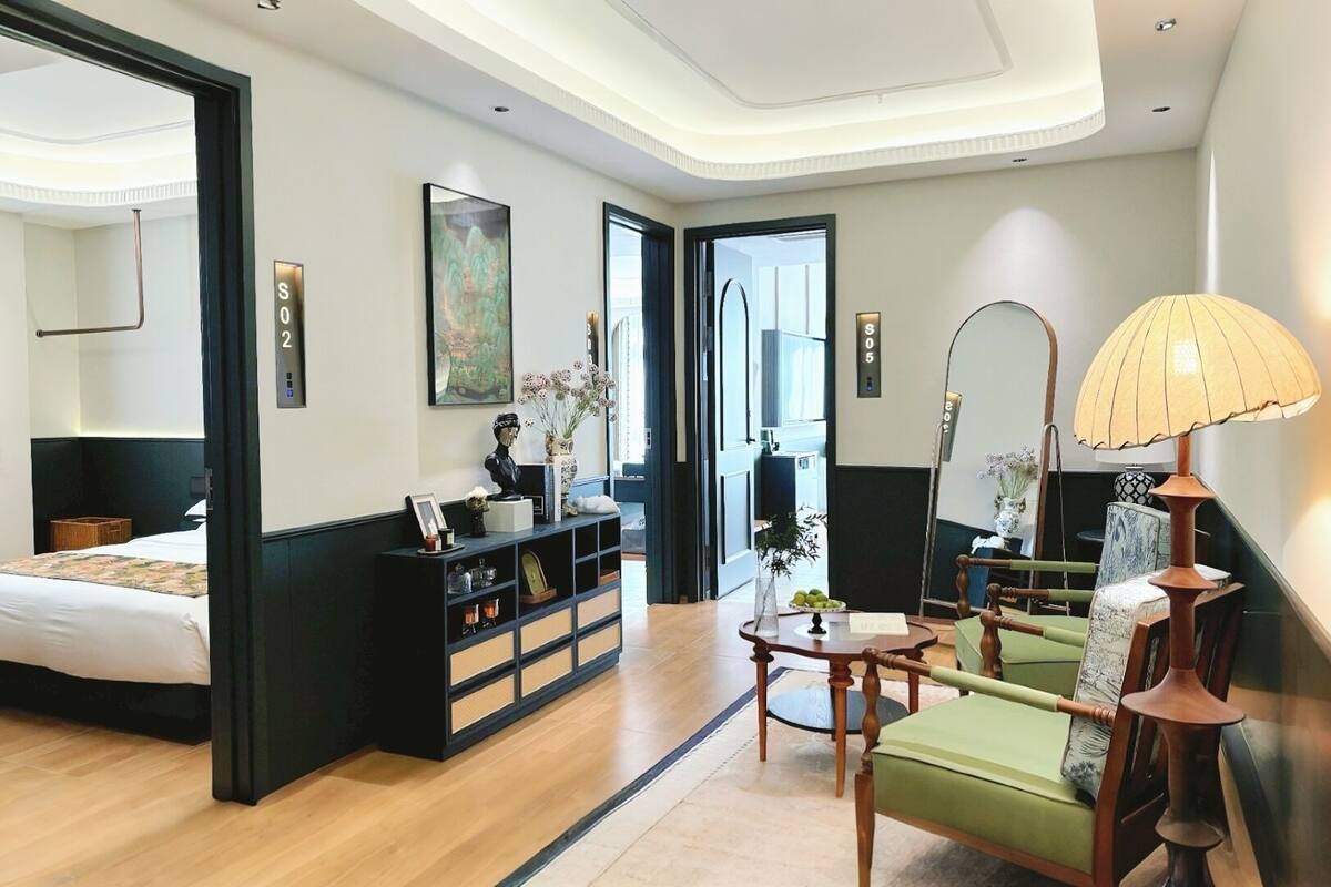 Una habitación de hotel moderna con una cama, un escritorio, una silla, una estantería y un espejo grande.