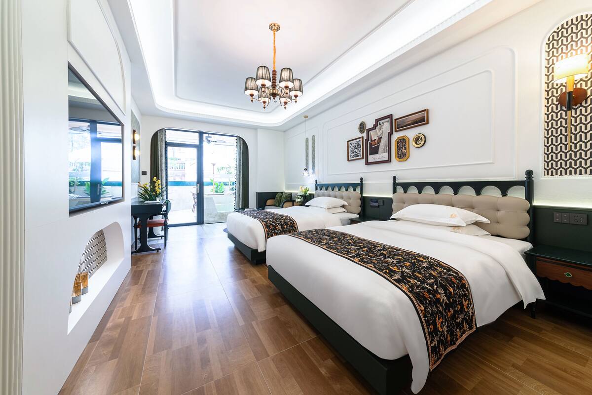 Una habitación de hotel moderna con dos camas, una araña y vistas al exterior.
