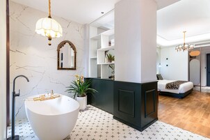 A modern bathroom with a freestanding bathtub, a large mirror, and a chandelier.