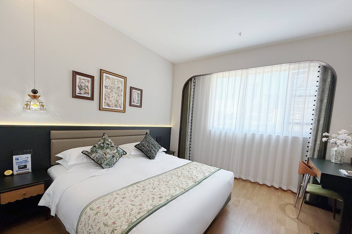 Una habitación de hotel con una cama, un escritorio y una silla. Hay tres cuadros en la pared.