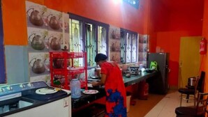 Une cuisine équipée d’une cuisinière, d’un évier et où une personne est en train de cuisiner.