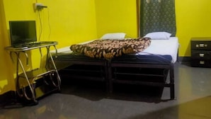 Une chambre avec deux lits, une petite table, un téléviseur et un rideau.