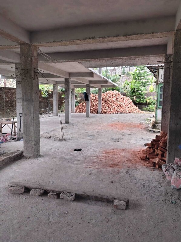 A construction site with exposed concrete pillars, a pile of bricks, and construction materials. - Hotel SDC (West Kameng)