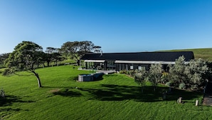 A modern building with a flat roof, surrounded by a well-maintained lawn and trees.