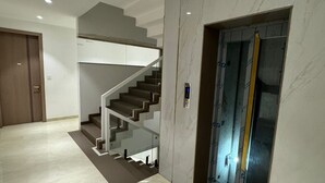 Un interior moderno con suelo de mármol, una escalera y un ascensor.