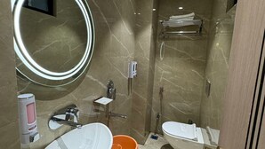 Un baño moderno con un espejo grande, dos lavamanos, una ducha y un inodoro.