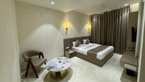 Una habitación de hotel con cama, mesita de noche, lámpara, silla y una mesa redonda.
