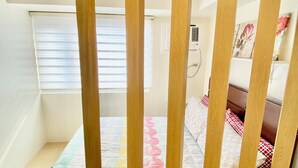 Een slaapkamer met een bed, een raam met zonwering, een wandairconditioner en een plank met decoratieve voorwerpen.