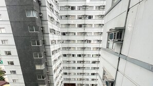 Een hoog gebouw met meerdere balkons, een zwembad en een kleine tuin.