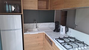 A compact kitchen with a refrigerator, sink, coffee maker, and gas stove. - Forestside Retreat in Turnhout (Turnhout)