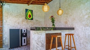 A kitchen with a refrigerator, a bar counter, and two wooden stools. - Villa Kuma Ubud (Tegallalang)