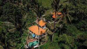 A two-story house with a swimming pool, surrounded by dense tropical vegetation. - Villa Kuma Ubud (Tegallalang)