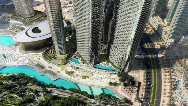 Un complejo de edificios altos con varios rascacielos, una plaza circular central y zonas verdes circundantes.
