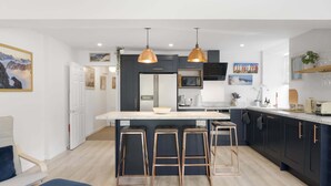 Een moderne keuken met een centraal eiland, barstoelen en hanglampen.