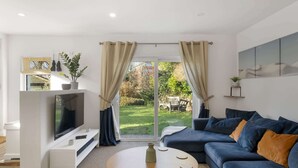 Ein modernes Wohnzimmer mit Fernseher, Sofa und Couchtisch.