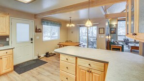 Une cuisine avec des meubles en bois, un grand îlot central et un coin repas comprenant une table et des chaises.