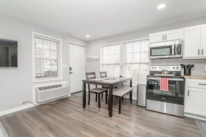 Una cocina moderna con armarios blancos, horno de acero inoxidable y una mesa de comedor con sillas.