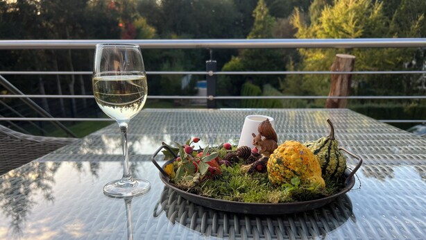 Une table avec un verre de vin blanc, un saladier rempli de salade et une figurine d’écureuil décorative.