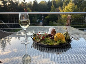 A table with a glass of white wine, a bowl of salad, and a decorative squirrel figurine.