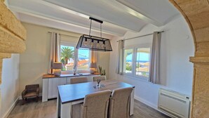 A dining area with a table and chairs, a hanging light fixture, and a view of the outside. - Casa Esmick - Denia, Costa Blanca (Denia)