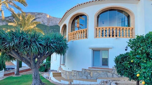 A two-story house with a stone facade, large windows, and a balcony. - Casa Esmick - Denia, Costa Blanca (Denia)