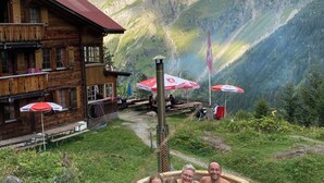 Eine Holzhütte mit Pool, umgeben von Bergen und Sitzgelegenheiten im Freien.