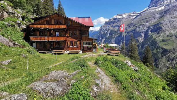 Eine Holzhütte mit rotem Dach, mehreren Balkonen und Außenmöbeln.