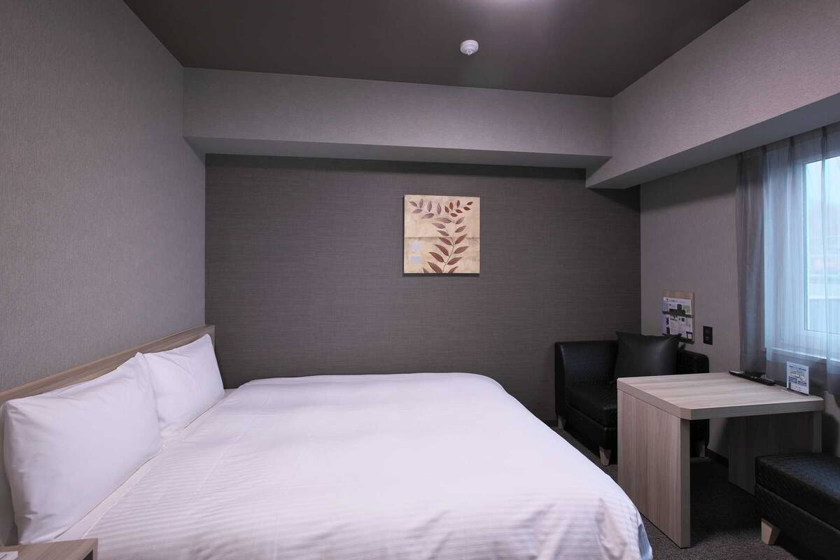 Ett hotellrum med en stor säng, ett skrivbord och en stol.