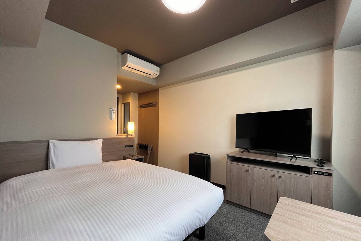 Ett hotellrum med en stor säng, en platt-TV, ett skrivbord och en garderob.