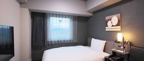 Habitación de hotel moderna con una cama grande, televisor de pantalla plana, escritorio y ventana con cortinas.
