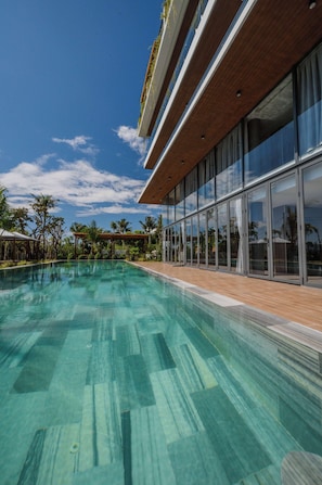 A modern pool area with clear water, wooden deck, and large glass windows. - Peppercorn Villas (Phu Quoc)