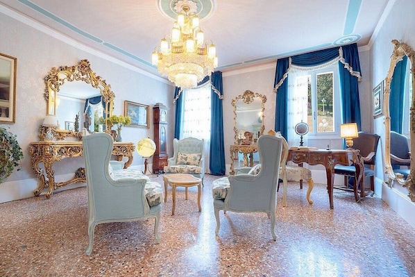 A room with a chandelier, ornate furniture, and a large mirror.