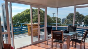 Ein geräumiger Balkon mit Glastür, Korbmöbeln und Blick auf die umliegende Natur und Bauten.