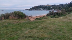 Eine Küstenlandschaft mit Sandstrand, grünen Wiesen und sanften Hügeln mit Häusern.