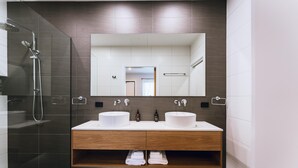 Ein modernes Badezimmer mit zwei Waschbecken, einer Dusche und einem großen Spiegel.