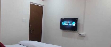 A modern hotel room with a bed, a flat-screen TV, a ceiling fan, and a marble floor.